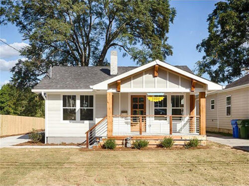 Small beige house with nice landscaping and front lawn