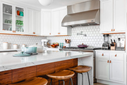 FixNFlip kitchen with wooden bar stools, white cabinets and gas stove