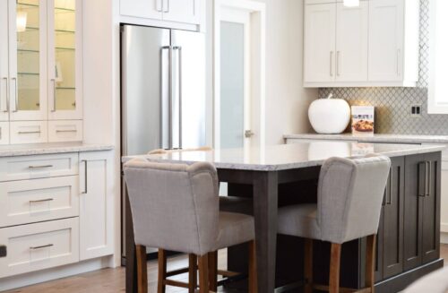 Clean kitchen with table built into island with white cabinets and modern appliances