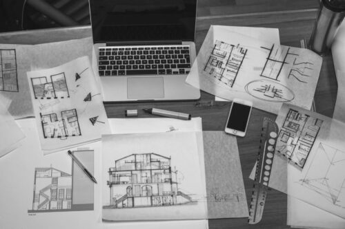 Floorplan drawings of house sitting on desk with computer and rulers