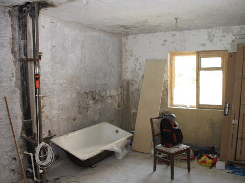 Old concrete room with tub and plumbing