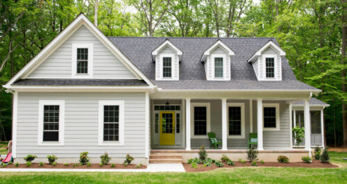 Exterior of a new Cape Cod styled suburban house with recently planted shrubs and grass