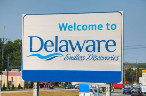 A "Welcome to Delaware" sign outside on the side of a road