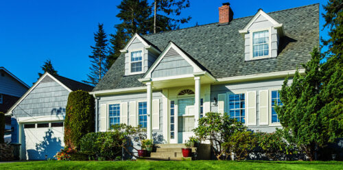 Two story home with adjacent garage and bright green grass